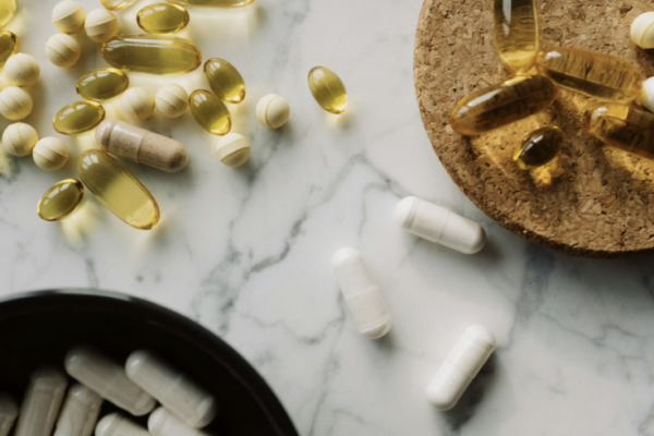 Femme en ménopause tenant un complément alimentaire vitamine D, lumière naturelle, fond doux — carence vitamine D ménopause